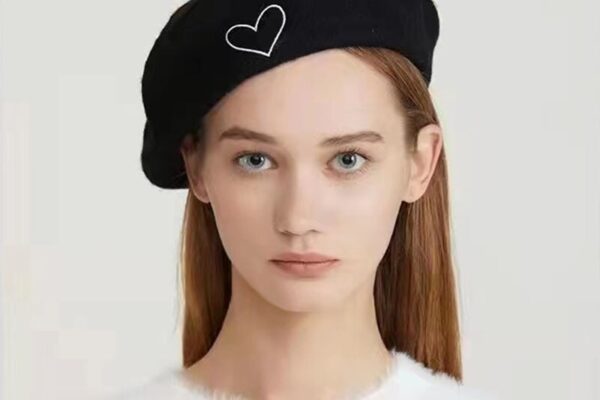 a girl worn black beret hat with a heart logo